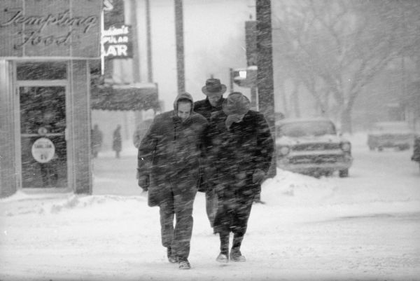 Pedestrians buck a stiff headwind walking along the Capitol square during a winter snowstorm that brought a 5-inch snowfall and stiff winds in Madison.