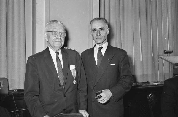 William T. Evjue, editor and publisher of the <i>Capital Times</i> (left), shown after receiving the Knight's Cross, First Class, Royal Order of St. Olav, from Norwegian Counsul Helge Akre (right) on behalf of the king of Norway. The medal is on the front of Evjue's jacket.