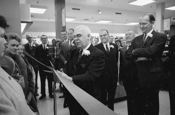 Lieutenant Governor Philleo Nash, center, cutting the ribbon to open the new million dollar J.C. Penney Co. department store located on the Capitol Square at 1 East Main Street. There is a WIBA microphone in the foreground.
