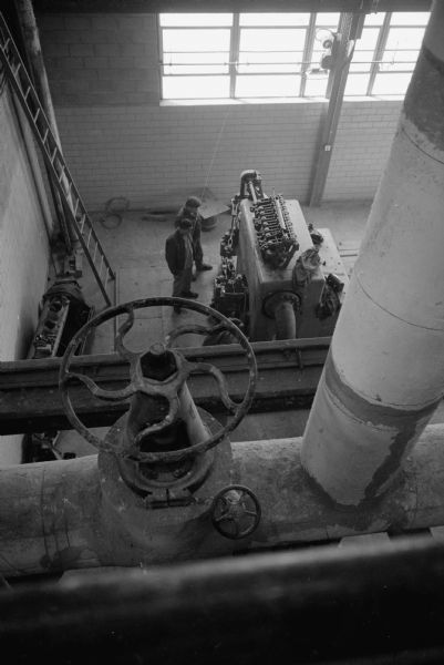 Workers Frank Kasiniski and Wilburn Gibson inspecting the generator and turbine room at the new University of Wisconsin heating plant located on Charter Street. 