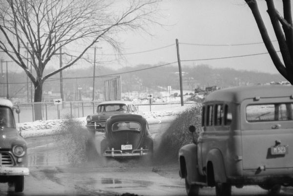 Cars driving through puddles from melting snow along North Shore drive near the Chicago & North Western railroad tracks.