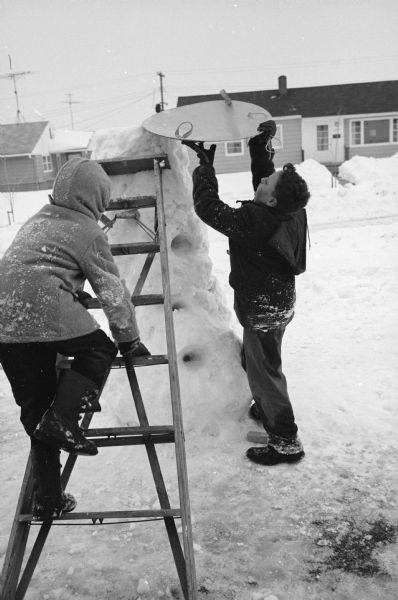 Larry (9) and Howard (13) Schwartz work at building a snow slide in their front yard at 4322 Wakefield Street.