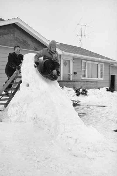 Larry Schwartz (9) starts his slide in a saucer on the homemade snow slide he and his brother Howard (13) built in their front yard at 4322 Wakefield Street.