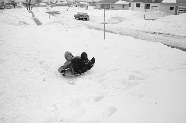 Larry Schwartz (9) sliding down the homemade snow slide on a saucer in his front yard at 4322 Wakefield Street. He and his brother Howard (13) built the slide.