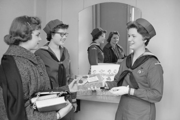 Pat Parent and Vicki Vauk, members of Scout Mariner Ship No. 4, present a preview of the Girl Scout cookies to Annetta Evenson, a University of Wisconsin coed who lives at Elizabeth Waters dormitory. The annual cookie sale of the Blackhawk Council of Girl Scouts was about to begin.