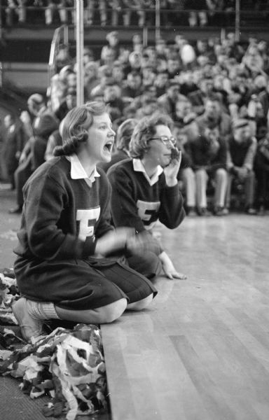Eau Claire Memorial cheerleaders Carol Bliss (L) and Janet Targart, Eau Claire Memorial, cheer for their team playing in the state basketball tournament. The game was played at the University of Wisconsin Field House.