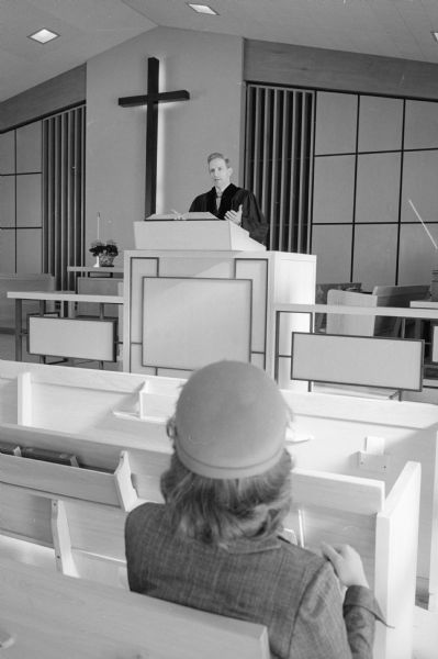 When Joan Carlton of Oakpark, Illinois married Reed Forbush of Appleton, Wisconsin she was skeptical of life as a minister's wife. Now, as a series of photographs shows, she enjoys her life as the wife of the pastor of Middleton Community church. Joan is sitting in a pew as her husband preaches.