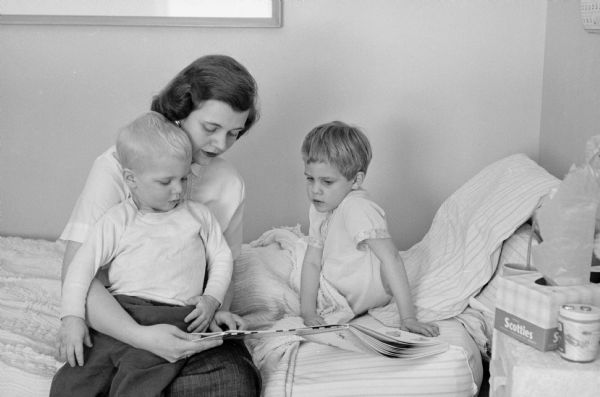 When Joan Carlton of Oakpark, Illinois married Reed Forbush of Appleton, Wisconsin she was skeptical of life as a minister's wife. Now, as a series of photographs shows, she enjoys her life as the wife of the pastor of Middleton Community church. Joan with her younger two children, Kyle and Christie Anne, who are sick with chicken pox.