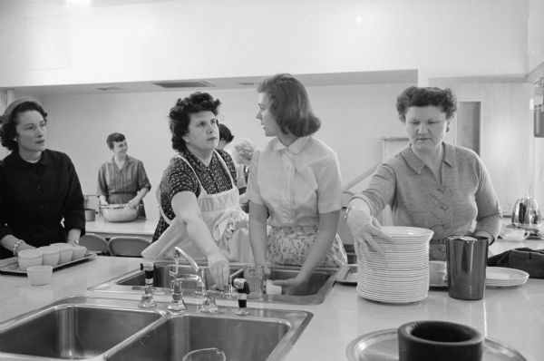 When Joan Carlton of Oakpark, Illinois married Reed Forbush of Appleton, Wisconsin she was skeptical of life as a minister's wife. Now, as a series of photographs shows, she enjoys her life as the wife of the pastor of Middleton Community church. After the church supper Joan helps with dishes.
