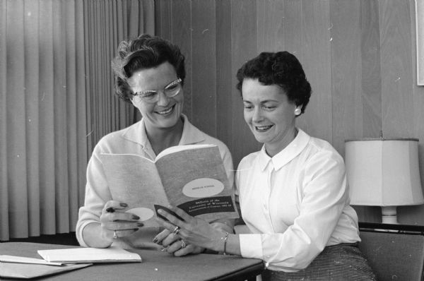 Mary Jefferson Davis and Nancy Taborsky viewing a book. They were co-chairwomen of the Dane County Medical auxiliary's benefit dinner dance. Proceeds went to scholarship and education funds.