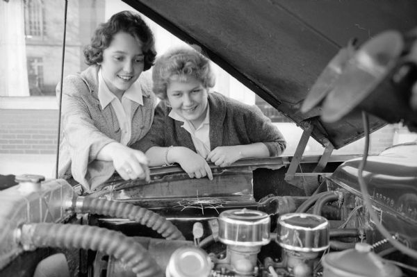 Many teenage drivers learn to drive in the summer driving education courses. Sue Hubbard, a student of the course, is shown explaining the parts of an engine to Terry Guess.