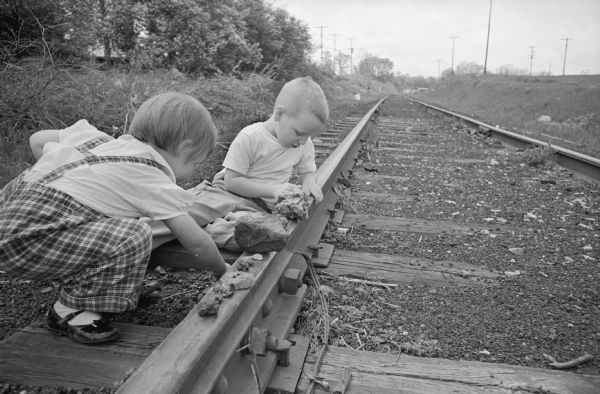 John and Jane Pike, who live near the Illinois Central railroad tracks, demonstrate for the photographer what they have been told not to do — put stones on the rails.