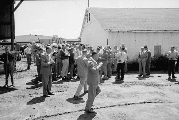 A group of 75 West German farmers visit Madison on a week-log tour of mechanized farming operations in the Midwest. The group stops at the Bowman Farm Dairy, Fish Hatchery Road, to observe the mechanized milking operation. 