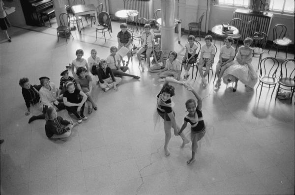 Forty girls, ages 8-16, participate in Madison's first consolidated children's fine arts program sponsored by the Y.W.C.A. Ann Hoffman of the Y.W.C.A. staff directs the program. The sessions are taught by U.W. graduate students. Lessons in ballet and modern dance; sketching, drawing, and watercolors. Drama and music are included in the program. Shown is freely interpreted dance in ballet style performed by Rosalie Messina (L), 1921 Jefferson Street, and Charlene Harris (R), 1901 Baird Street. 