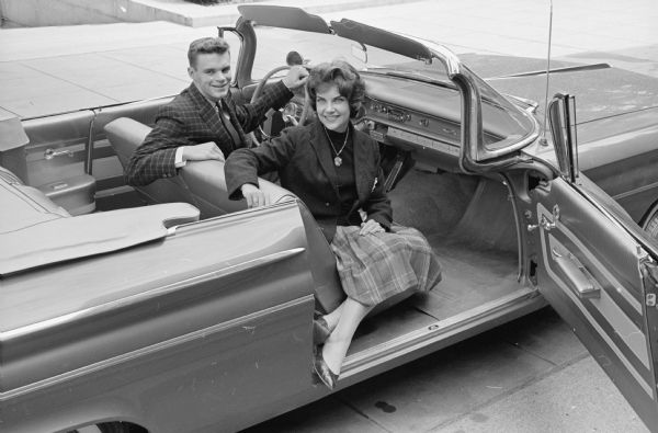Two Monona Grove high school graduates who are now freshmen at the University of Wisconsin, Dean Wichern and Carolyn Wurz, shown dressed to go to a football game. Dean is wearing a sport coat and tie, and Carolyn is wearing a plaid wool skirt with a black cashmere slip-over sweater and black blazer.