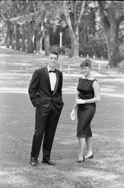 Jeffrey Renk and Annette Letendre, Madison Edgewood high school graduates and freshmen at the University of Wisconsin pose in formal attire for attending formal parties. Jeffrey is wearing a tuxedo and Annette is wearing a sophisticated type of dress with high square neckline, wide cummerbund, and scalloped hem.