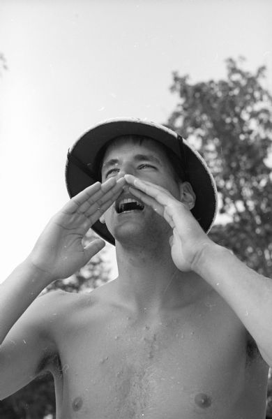Angello LaBarro, a lifeguard at a Madison beach, shouts a warning to an errant swimmer. He is a graduate of Madison East high school and has attended the University of Wisconsin for three years, and one year at a school in Madrid, Spain. He will be returning to Madrid for his second year of school there.