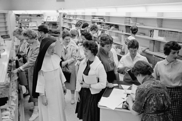 The new De Ricci Hall on the Edgewood College campus opens for the fall semester. The building houses both classrooms and administrative offices. Sister M. Claudette, O.P., is shown with students supervising the school book store.    