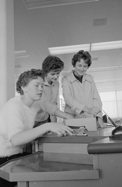 When their furniture finally arrived at the new CUNA Mutual Insurance Society building, these three women went to work straightening it up so that they'd be ready when the office opens for business Monday morning. Lynn Victor, 46 N. Park Street, center and Betty Lamb, Brooklyn, right help Nancy Clements, 1232 Spaight Street, put her desk in order.