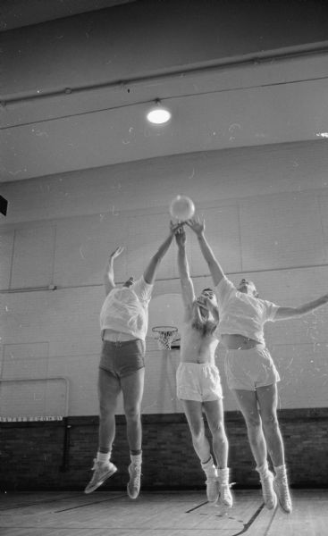Ed Volker (left), Tom Geppert (center), and Jim McIntosh reaching for the ball at the net during a volleyball clinic at the Madison YMCA.
