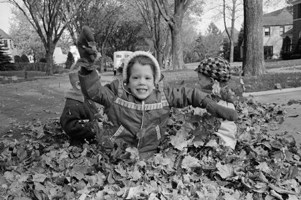 Five year-old Paula Scharch sitting in a pile of leaves.