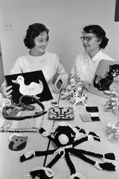 Two unidentified women from the St. Anne Society of St. Mary of the Lake Catholic Church stand by a display of items to be sold at their bazaar in the church's parish hall.