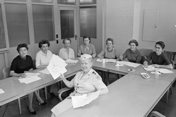 Dorothy Schar, chairman of volunteers for Madison Red Cross, holds up diplomas to be awarded after two months of training to be social welfare aides in the military and veterans program. The six ladies waiting to receive their diploma are, (left to right) Betty Waldvogel, Helen Curvin, Mildred Wirka, Gail Knight (home service chapter director), Edith Norman, Lucy Haspell, and Elizabeth Sewell.