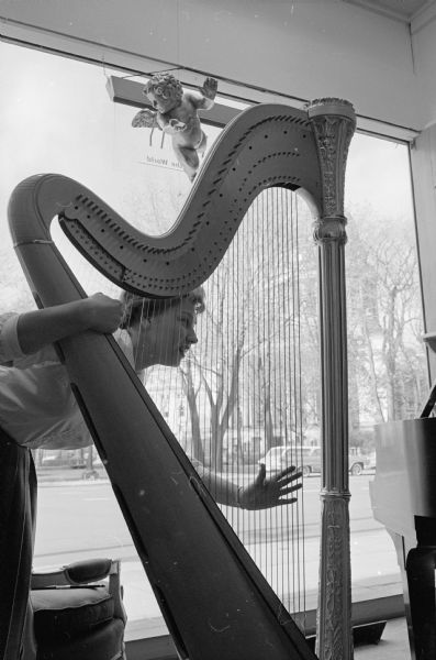 Helen Kowalke, an employe of Forbes-Meagher Music Company, tries out the harp on display at the store.
