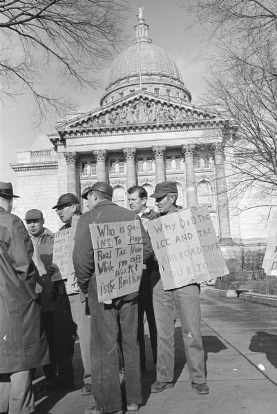 A group of truck drivers from Kenosha picketing at the State Capitol. They are protesting Interstate Commerce Commission (ICC) rate orders involving transportation of auto transport trailers on railroads.