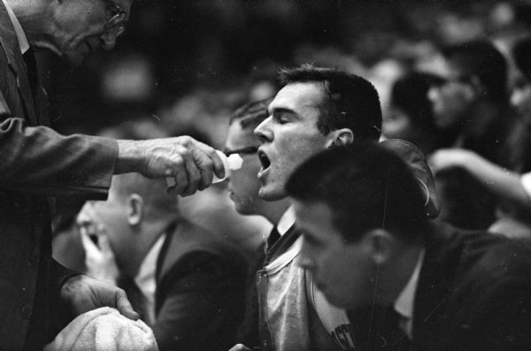 Wisconsin player Marty Gharrity gets a moisture spray from a trainer after coming out of the basketball game between Wisconsin and the Air Force Academy in the University of Wisconsin Field House.