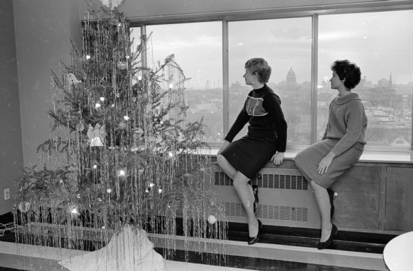U.W. Chadbourne Hall residents view a Christmas tree put up in the second floor lobby of the dormitory. The State Capitol is in the background. Shown (L-R) are Bridget Brenzel, a freshman from Kaukauna; and Judy Langenfled a freshman from Theresa.