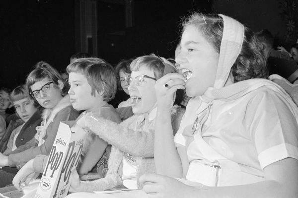 The 6th annual Madison school safety patrol Christmas party is held at the Strand Theater. The children are entertained by cartoons and a comedy feature film. Christmas bags filled with treats are passed out to the children. The party is sponsored by the Madison Police Department, Madison Board of Education and Madison Chamber of Commerce. Shown enjoying popcorn and the show are (L-R) Diane Lauber, 5033 Flambeau Road; Jo Anne Reynolds, 918 Oak Street; and Marie Abitanti, 917 Drake Street.