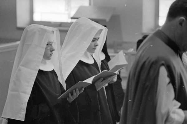 During a High Mass at the Academy of St. Benedict, Novice Sisters Mary Christine, left, and Mary David in white veils profess their temporary vows in the order of St. Benedict.