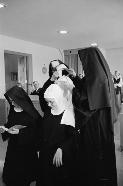 During a High Mass at the Academy of St. Benedict, black veils are placed on the heads of Novice Sisters Mary Christine, left, and Mary David as part of a ceremony of professing their temporary vows.  