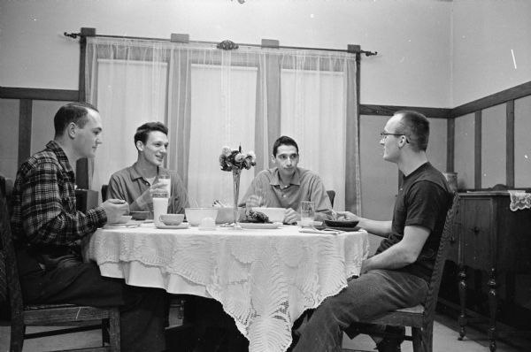 One in a series of photographs of U.W. four physics graduate students who are renting a furnished home at 429 Russell Walk. Sharing a meal are, left to right: Mark Daehler, Brandt Kehoe, Reinhard Graetzer and Dick Brown who cooked the meal.
