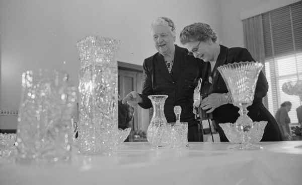 Ella Carter photographs the exhibit of cut glass items brought to the hobbies and craft show of the Woman's club of Madison by Ida Kittleson, who is on the left.