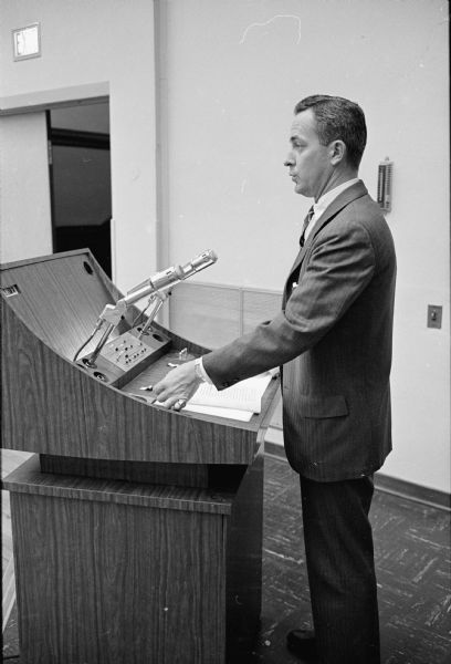 Telemation, a revolutionary audio-visual method of presenting instructional material was premiered at the University of Wisconsin education building auditorium. Raymond Hagen, a communications specialist from Teleprompter Corporation, stands at the control panel that projects audio-visual material that supplements his spoken word.
