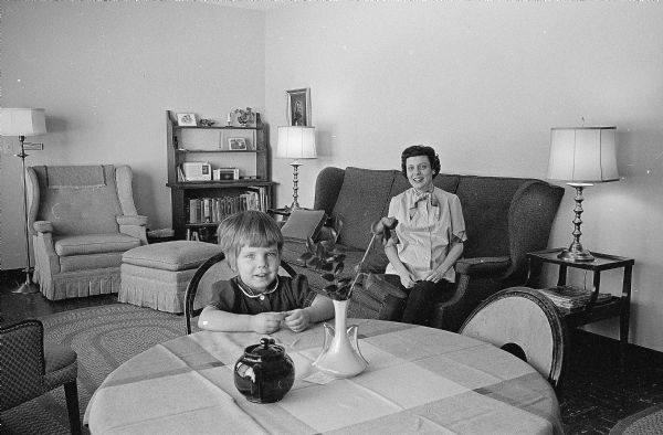 One of a series of photographs depicting ways U.W. graduate students have made their small apartments more livable. Shown is Mrs. Robert Rapp with her 2-year-old daughter Susie, who is seated at a card table that serves the family as a temporary dinette set.