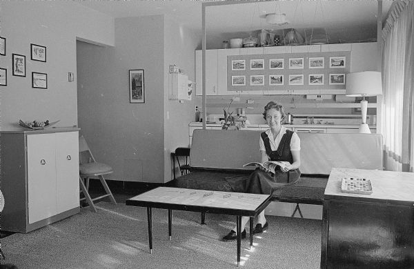 One of a series of photographs depicting ways U.W. graduate students have made their small apartments more livable. Shown is Mrs. Robert Walters. She and her husband made all the furniture for their living room, sofa beds from doors, a mosaic coffee table, cabinets, and a fancy room divider.