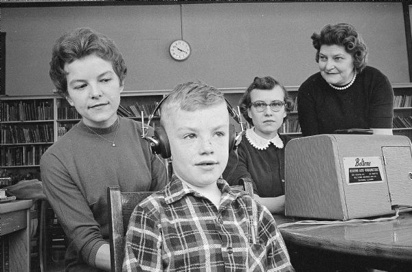 Seven-year-old Billy Roughton, wearing earphones, having his hearing tested by Barbara Dahle, left, a public health nurse with the Madison Health Department. With Billy are his mother, and Mrs. Lewis Roughton, and Freida Klusinske, volunteers for the hearing screening test.