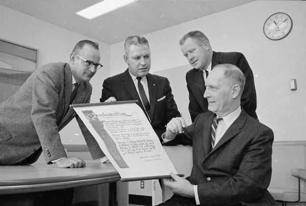 Mayor Harold E. Hanson, seated, displays a proclamation hailing the part played in American society by the advertising industry. Looking on are, left to right: Don Schaefer, Madison Newspapers; Hugh Brady, Stephan and Brady advertising agency; and John Beyler, Borden company.