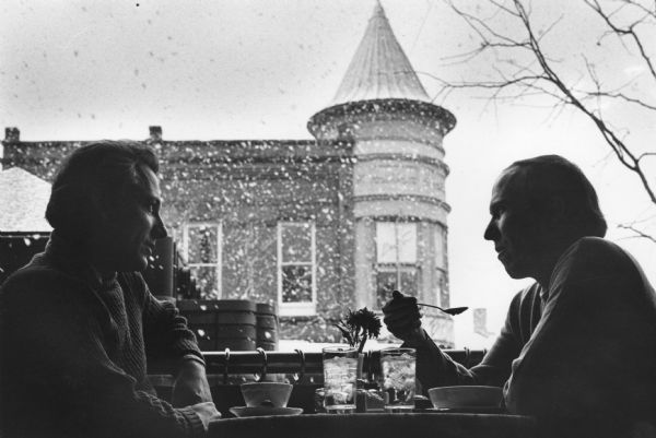 Two men sharing a meal at Ovens of Brittany on State Street during a snowy day.
