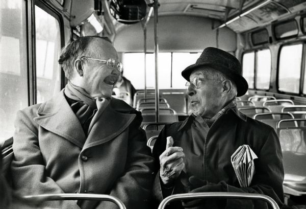 Two men enjoying a conversation while sitting together and riding on the Sherman Avenue bus.