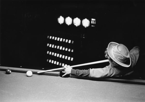 A boy wearing a hat is lining up a pool shot at Cue-Nique Billiards Hall on W. Gorham Street.