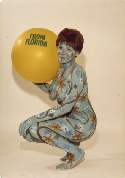 Front view of "Beach Ball Girl." The painted model is crouching and holding an orange beach ball with "From Florida" printed on the front.