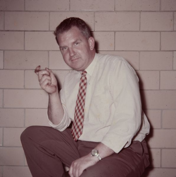 Waist-up portrait of Sid sitting indoors at Gisholt and holding a cigar. 