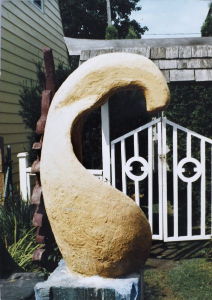 Sid's sculpture "Biomorphic Form with Anchor" in front of a gate. 