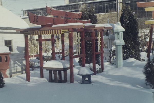 View of Sid's backyard, with a Japanese structure and sculptures in the snow. Madison-Kipp Corporation is in the background. 