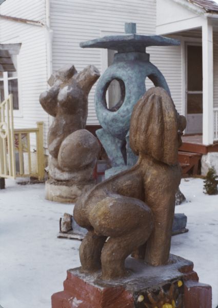 Group of Sid's sculptures in his backyard: "Blue Tripod," "Biomorphic Female Abstract in Pink" and "Guardian Lion." The back porch of the house and a side gate are in the background.