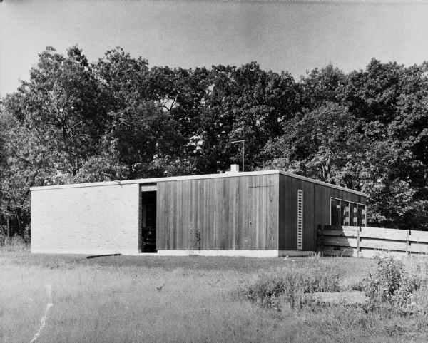 Arthur Boseler House, Keck and Keck Project #507. Project date 1954.  This photograph shows a side view of brick carport and an angled view of the vertical wood panels on the back of the Boseler house in Olympia Fields, Illinois.